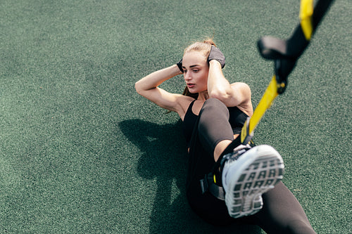 High angle view of woman athlete doing abdominal exercises using suspension straps