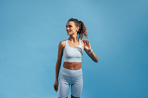 Young woman with slim healthy body standing against a blue wall