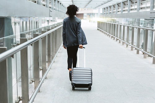 Back view of businesswoman walking with suitcase