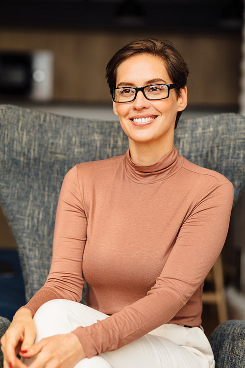 Portrait of a smiling entrepreneur in glasses sitting on armchair