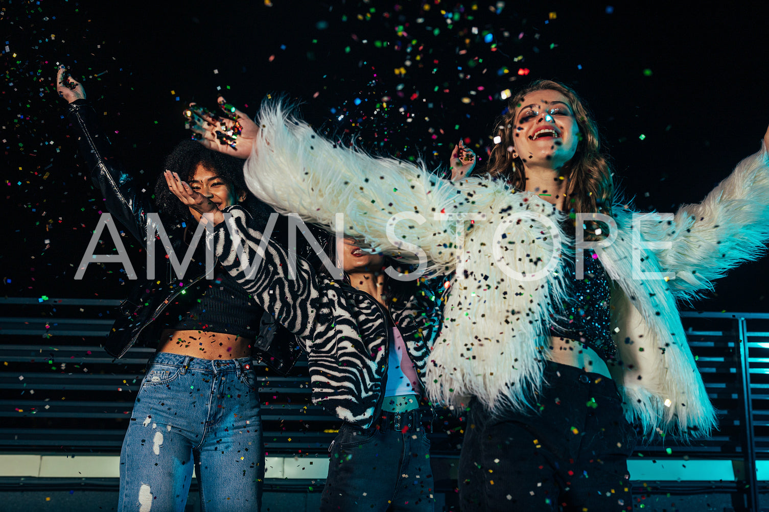 Three happy girls enjoying party. Female friends throwing confetti together and standing under him.	