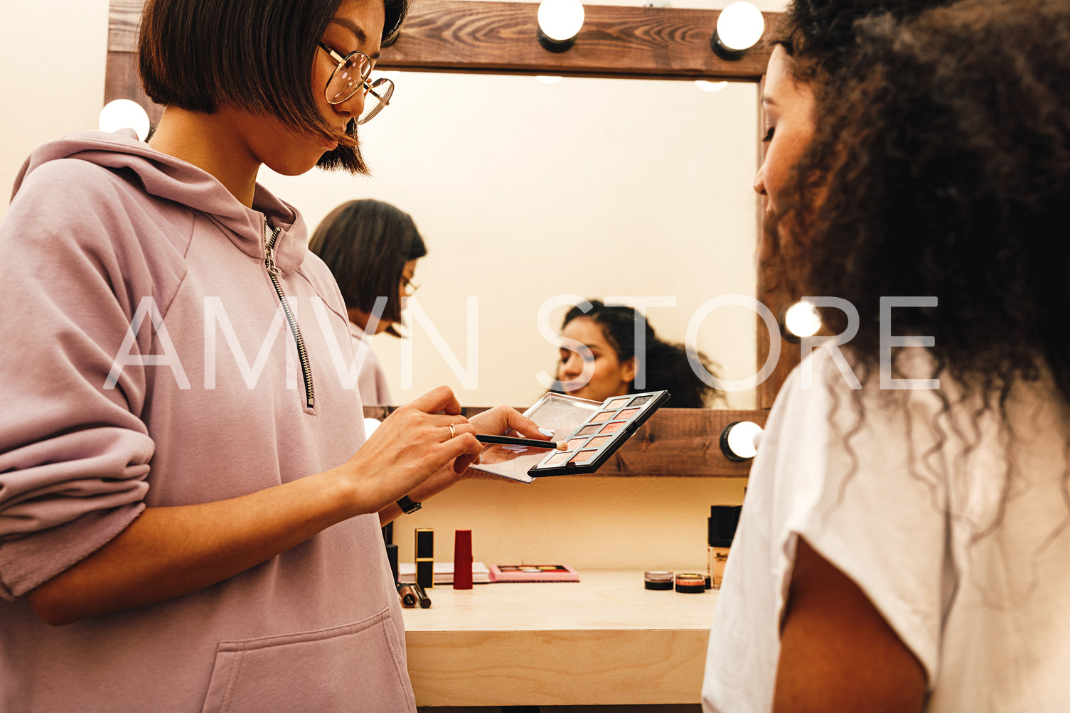 Makeup artist with her palette choosing color. Two people preparing for photo shoot.	
