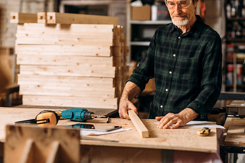 Cropped shot of mature carpenter standing at workbench in workshop