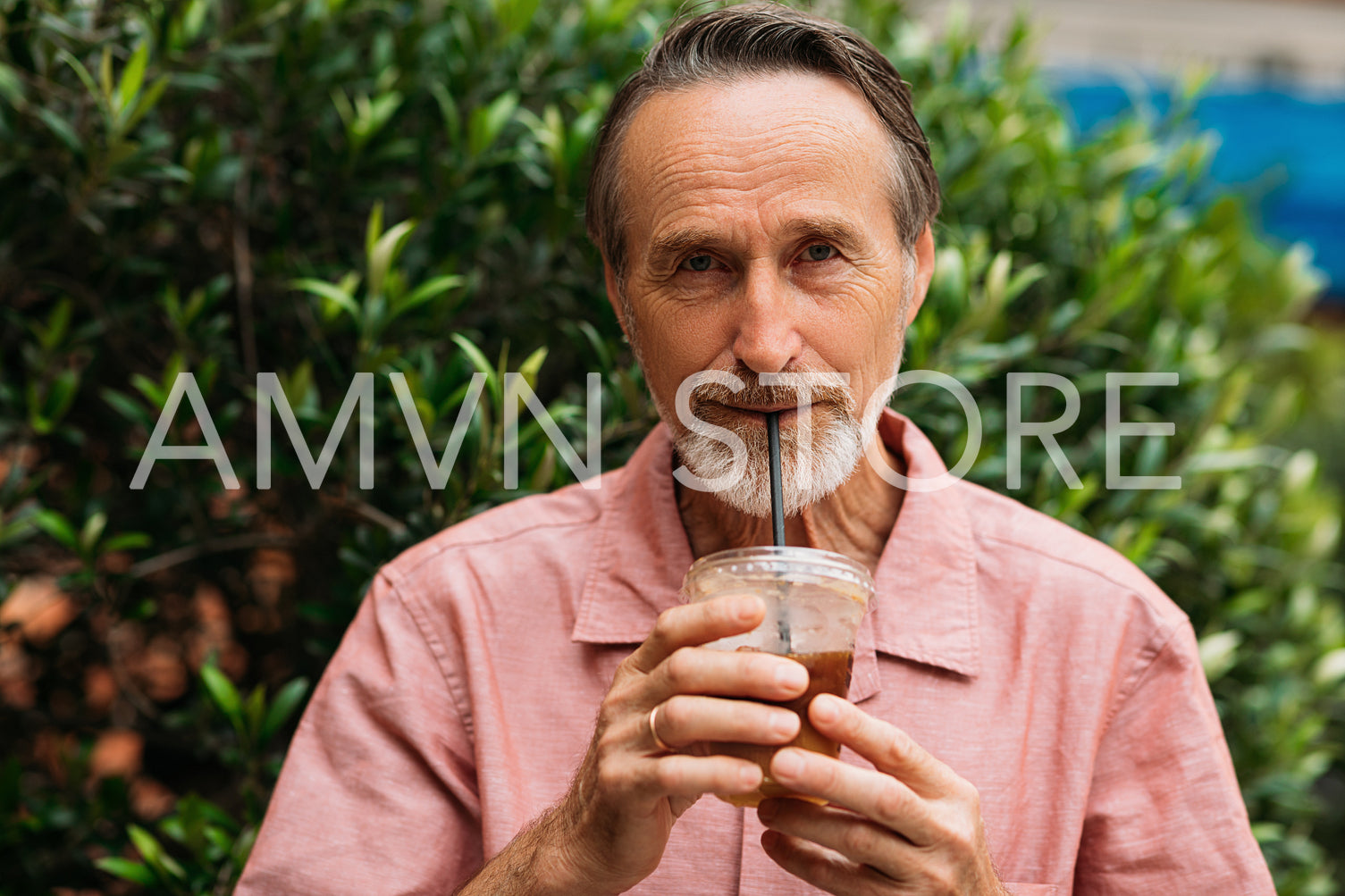 Senior man drinking a smoothie and looking at camera while standing on the park