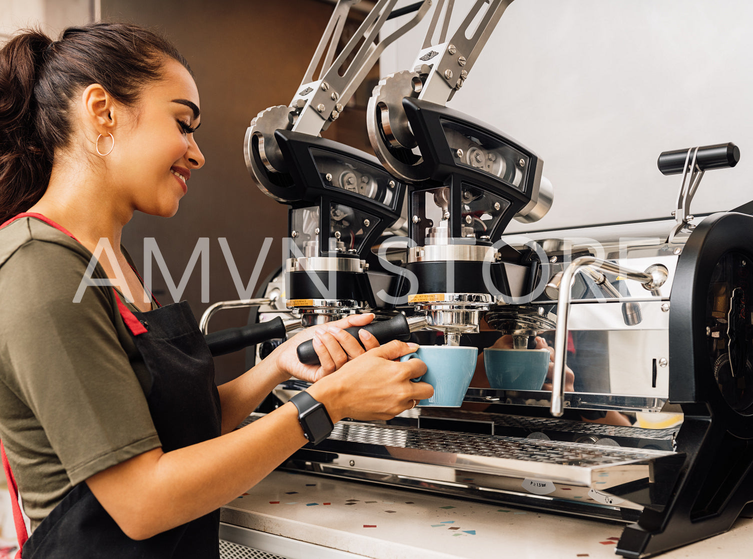 Female barista using a coffee machine. Smiling woman pouring hot coffee into cup at cafe.	