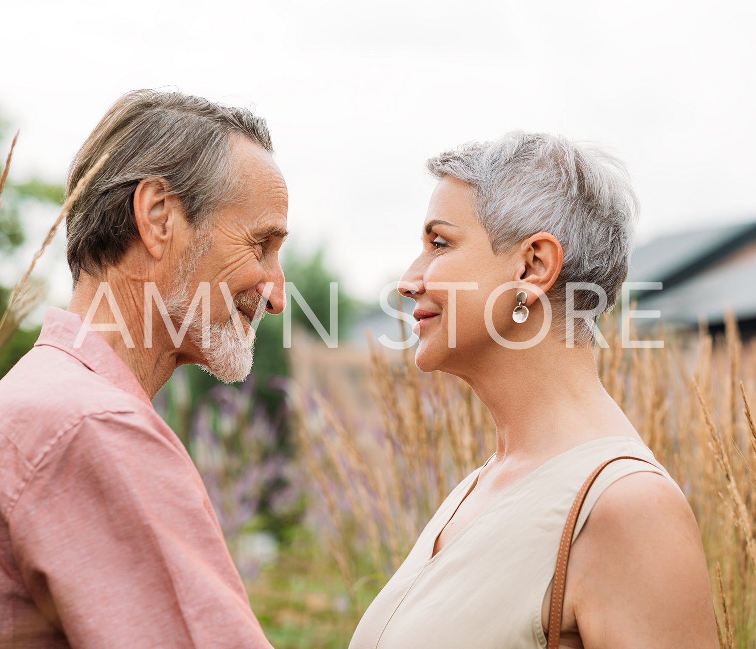 Aged couple looking at each other while standing on a field of wheat