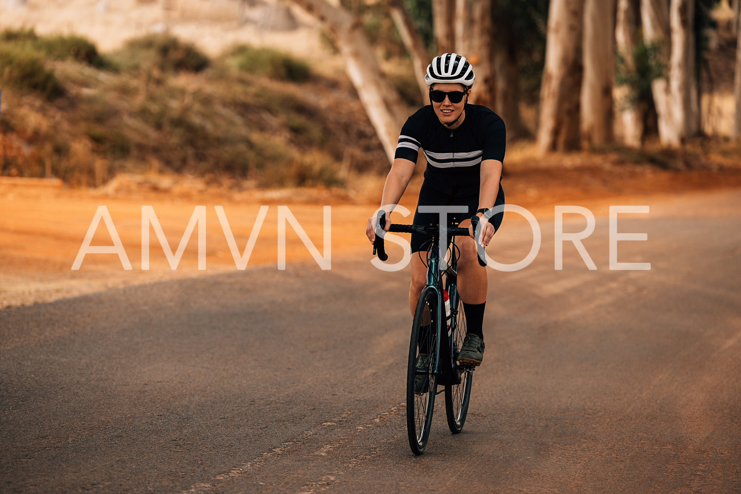 Woman cyclist wearing helmet and sunglasses riding outside on countryside road