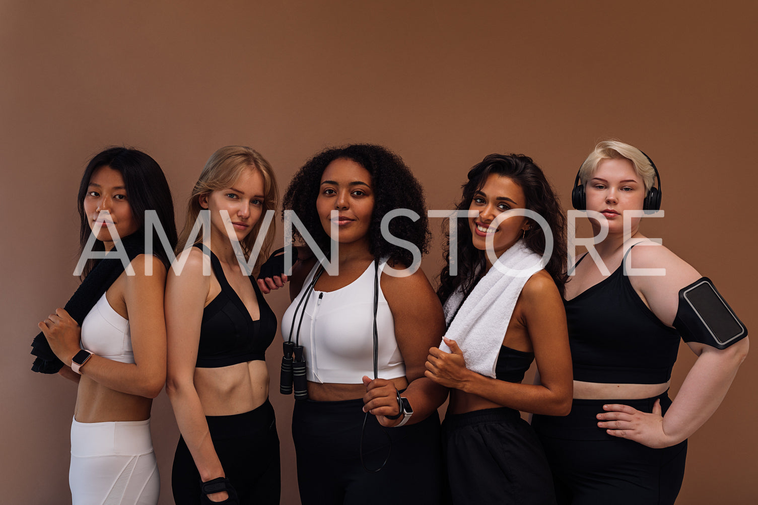 Group portrait of a five women in sportswear standing together on brown background