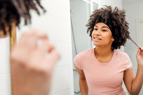 Girl holding up a strand of hair in her bathroom