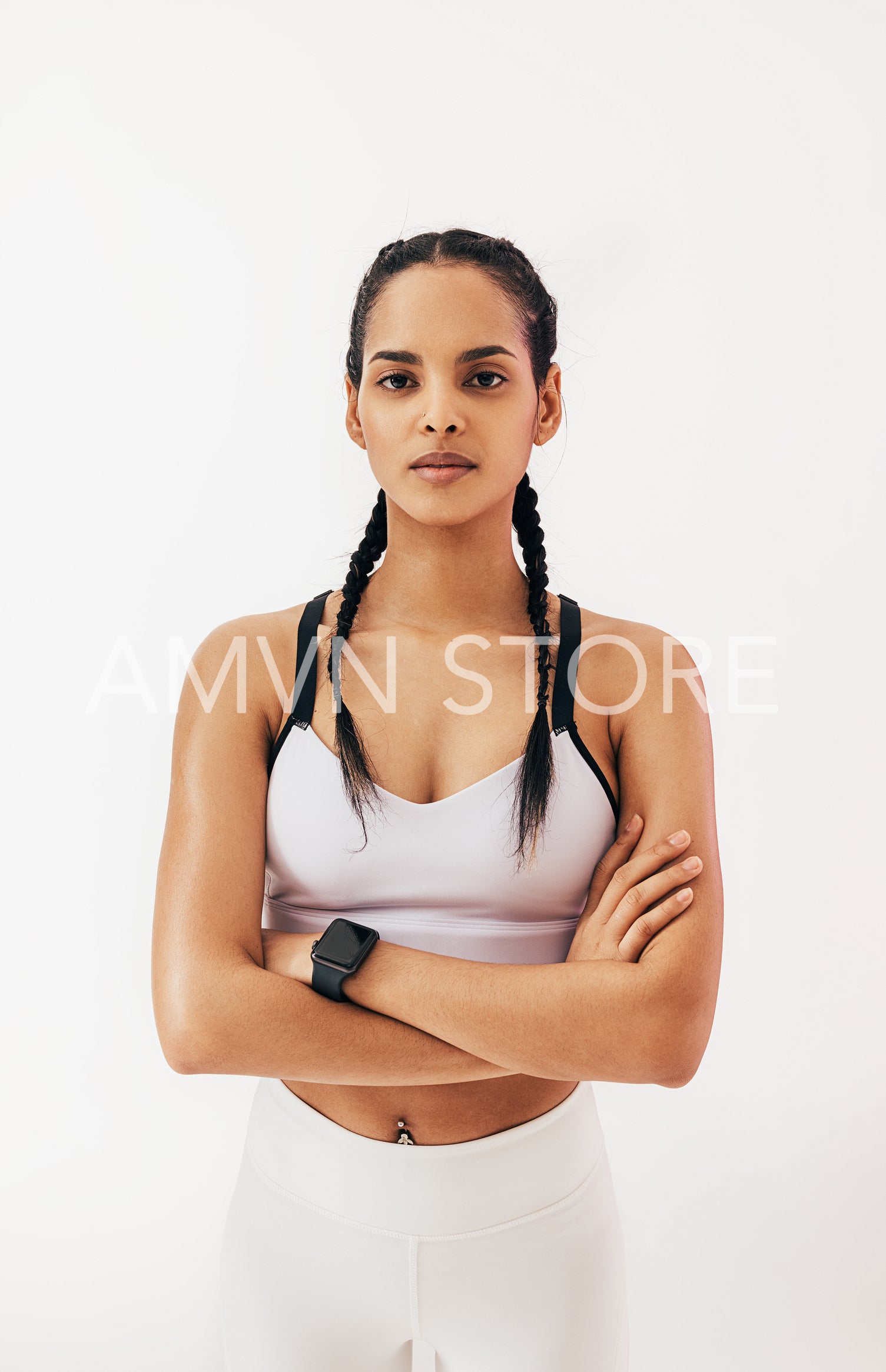 Confident fitness woman with braids standing in studio and looking at camera