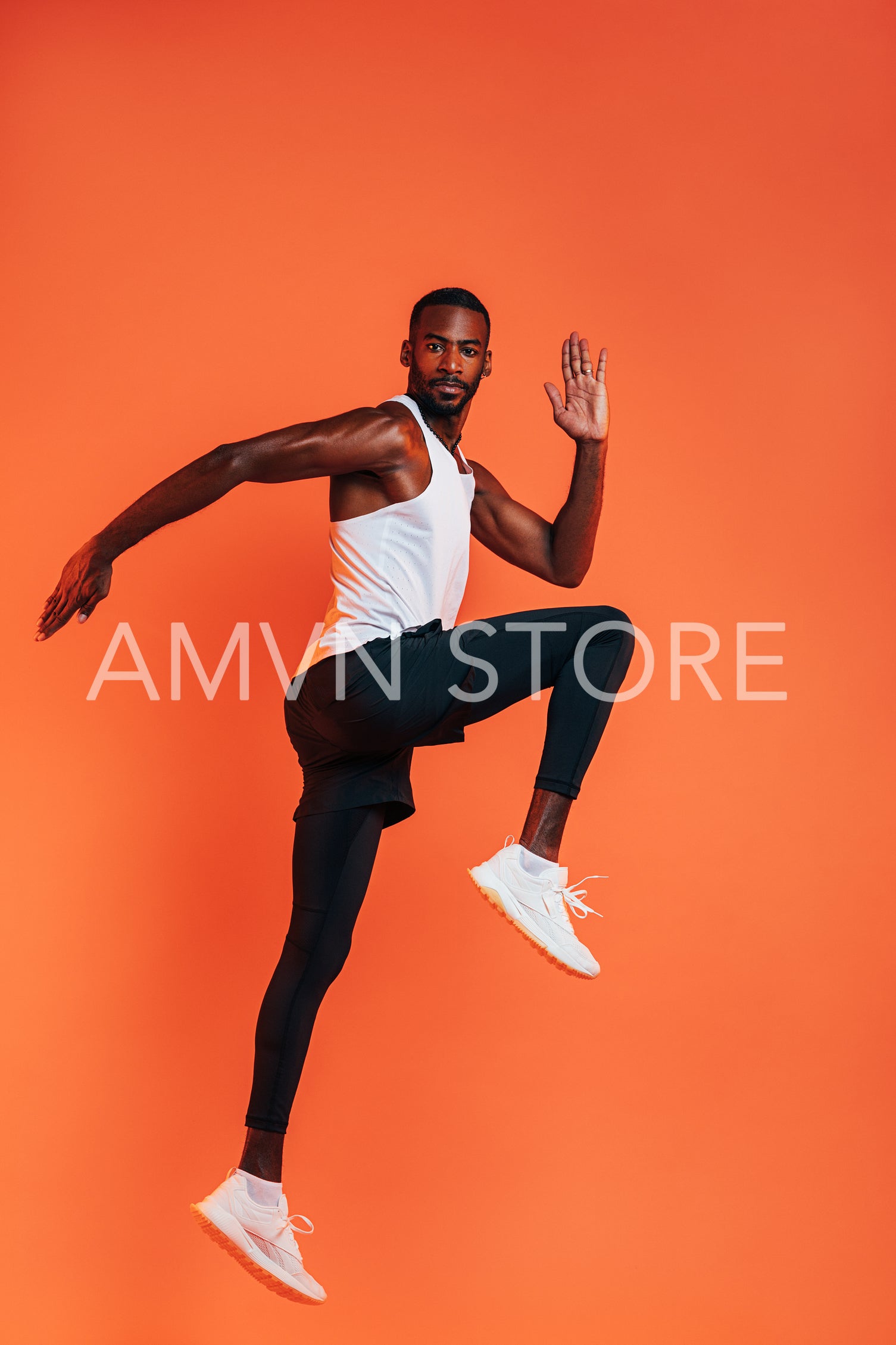 Sportsman doing a stretching workout. Full length of healthy fitness man exercising against an orange background.