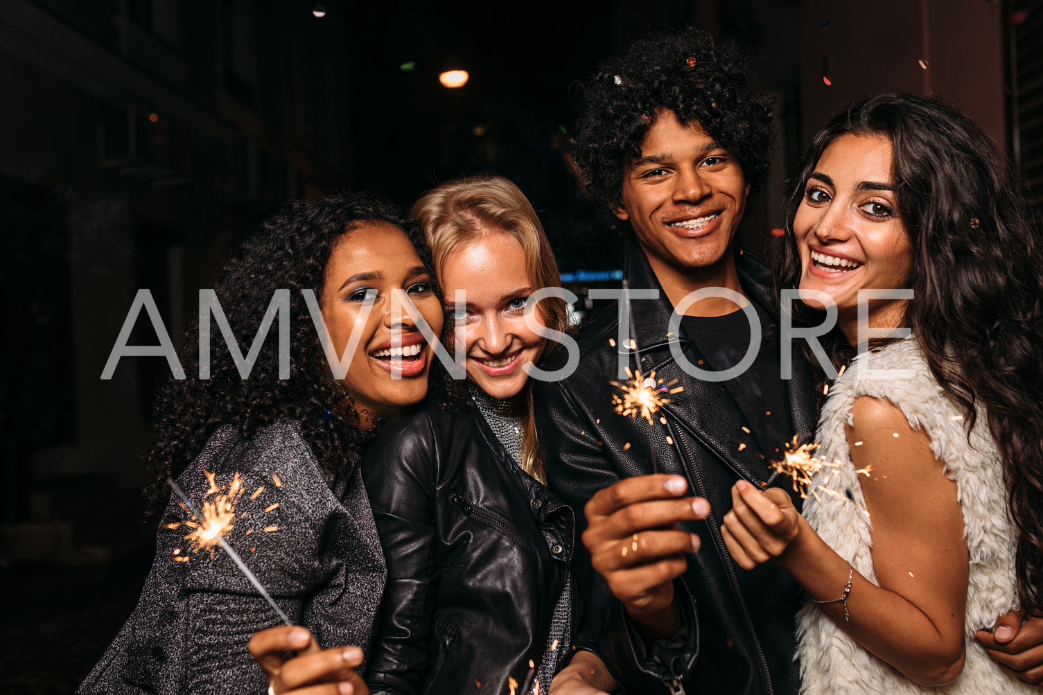 Group of young friends holding sparklers, looking at camera	