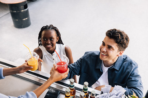 Two happy friends takeaway drinks from a food truck. People buying street food.