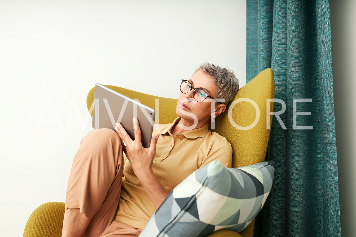 Stylish senior woman relaxing at home reading from digital tablet	