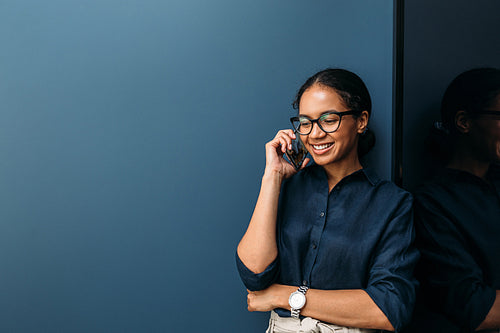 Smiling woman making phone call from home standing at wall