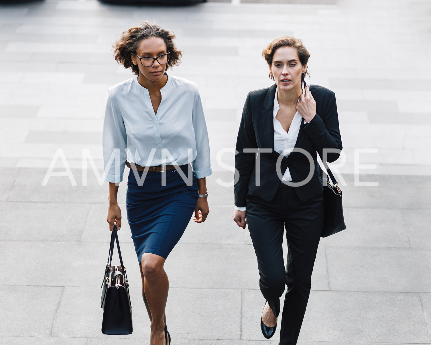 Two women in office wear stepping up on stairs in the city	