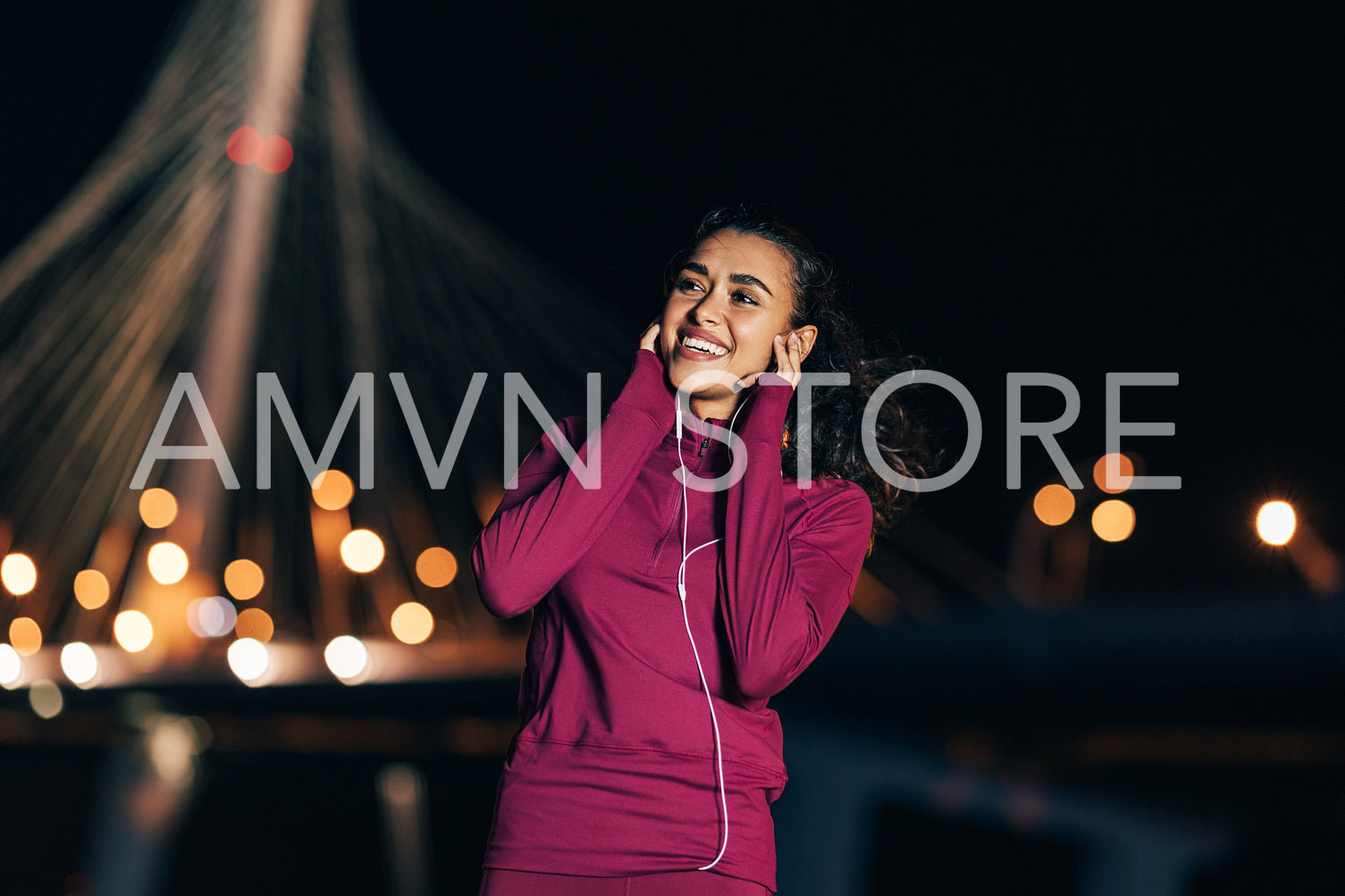 Cheerful woman in sport clothes enjoying music while standing at night