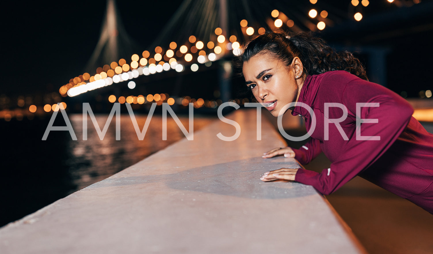 Young mixed race female athlete doing push-ups on an embankment at evening