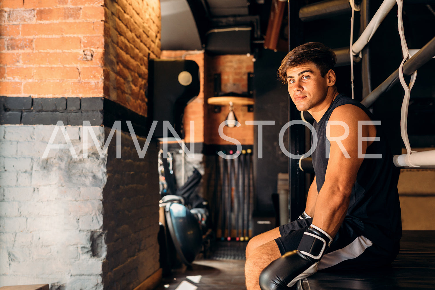 Side view of a young boxer sitting in gym	