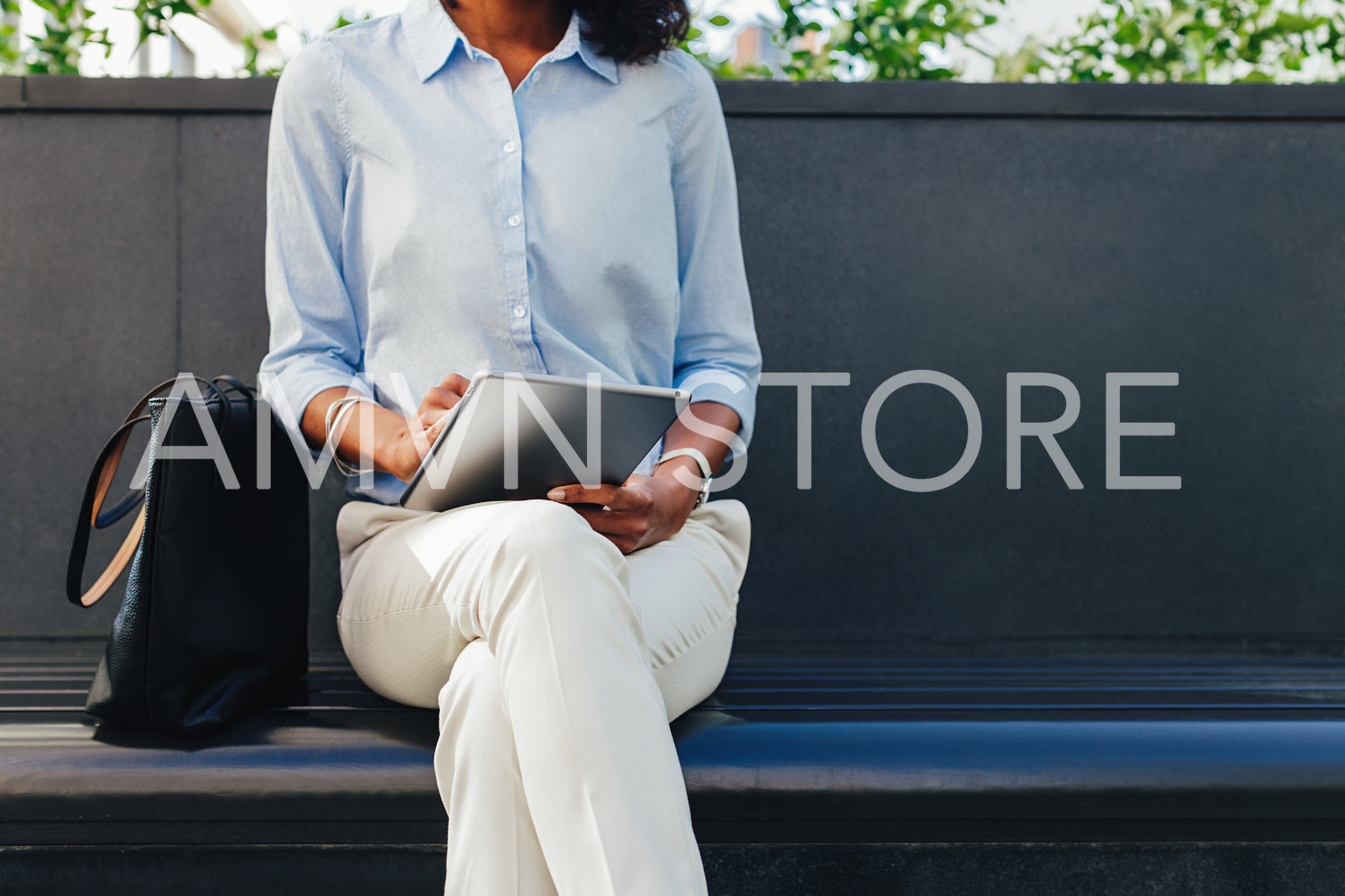 Unrecignizable businesswoman sitting at office building and using digital tablet	