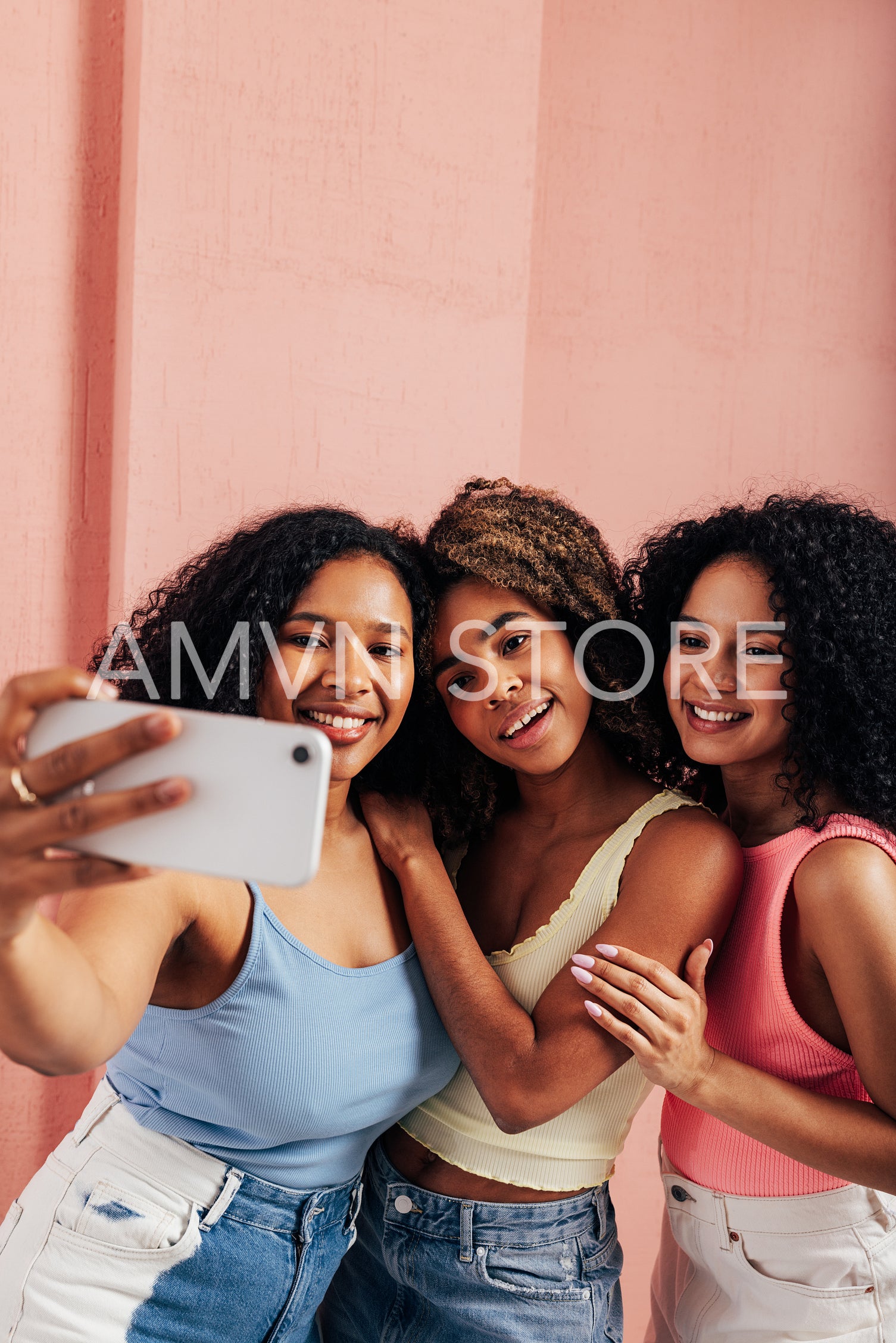 Three beautiful women with curly hair taking selfie on mobile phone 