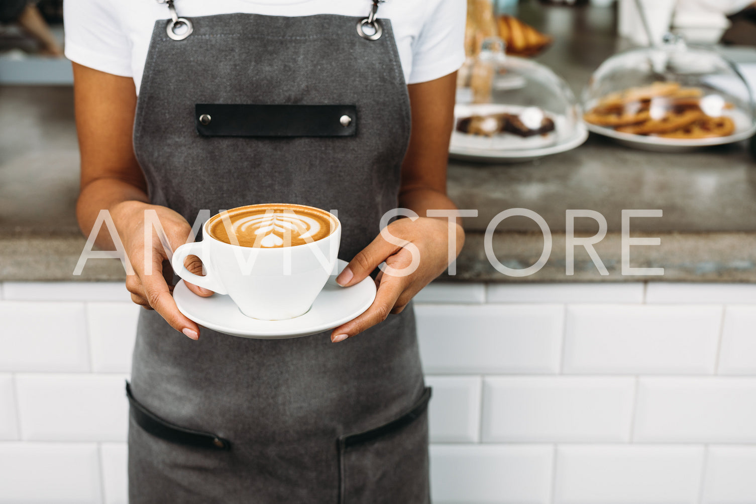 Unrecognizable waitress holding a cup of latte with rosetta in cafe	