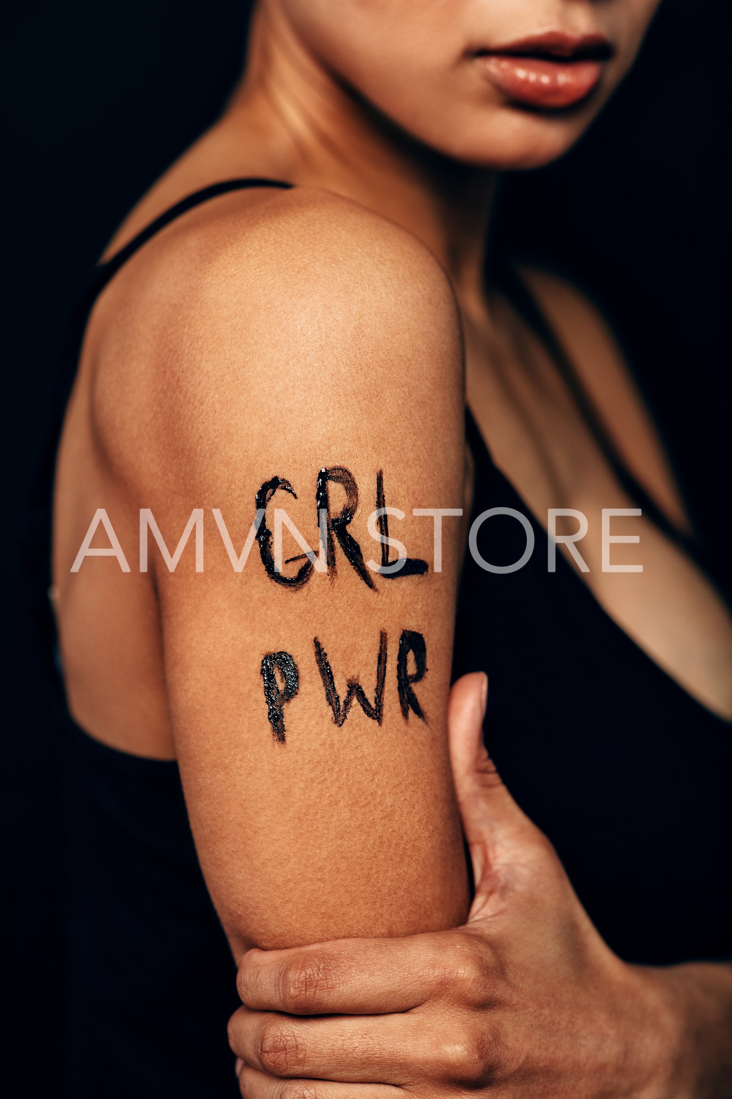 Studio shot of unrecognizable woman with letters "GRL PWR" on her shoulder	