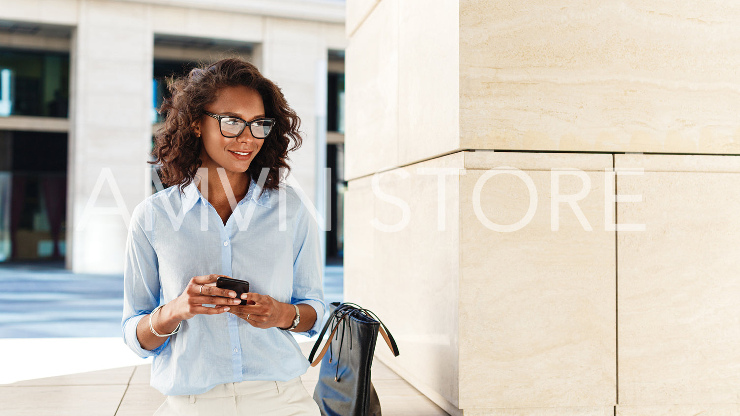 Smiling woman with smartphone in her hands. Entrepreneur standing outdoors and looking away.	