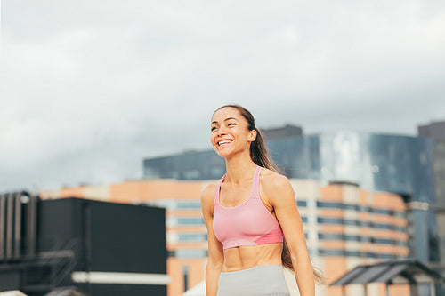 Happy female athlete in sportsclothes on the roof