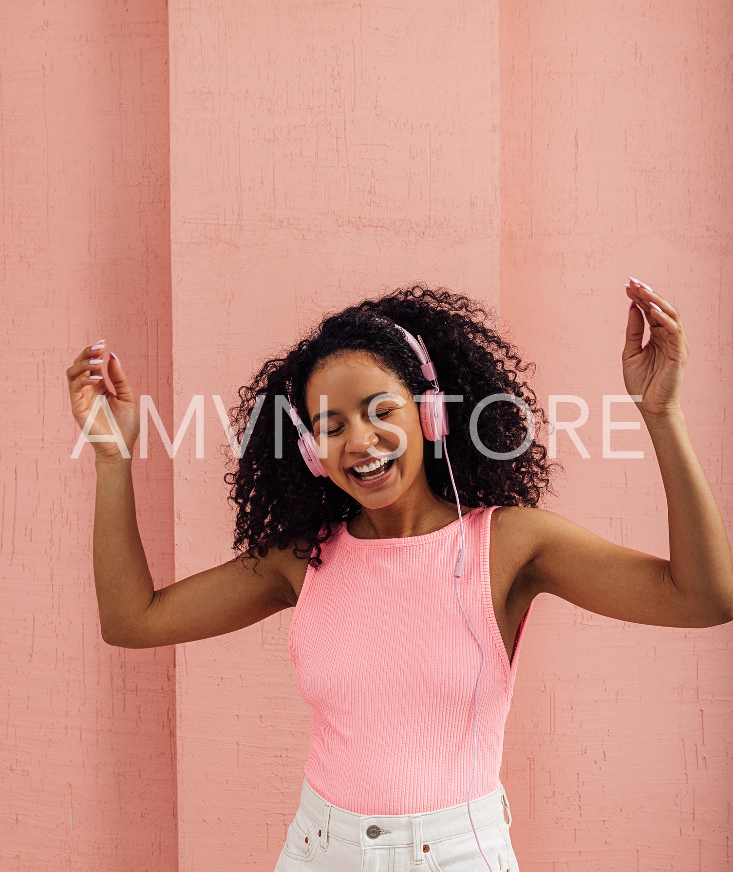 Happy woman wearing pink headphones enjoying music with closed eyes