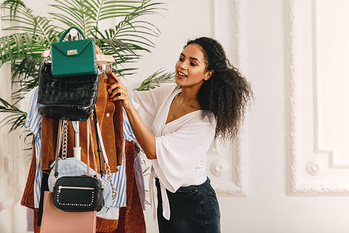 Young woman with curly hair looking at clothing on her rack