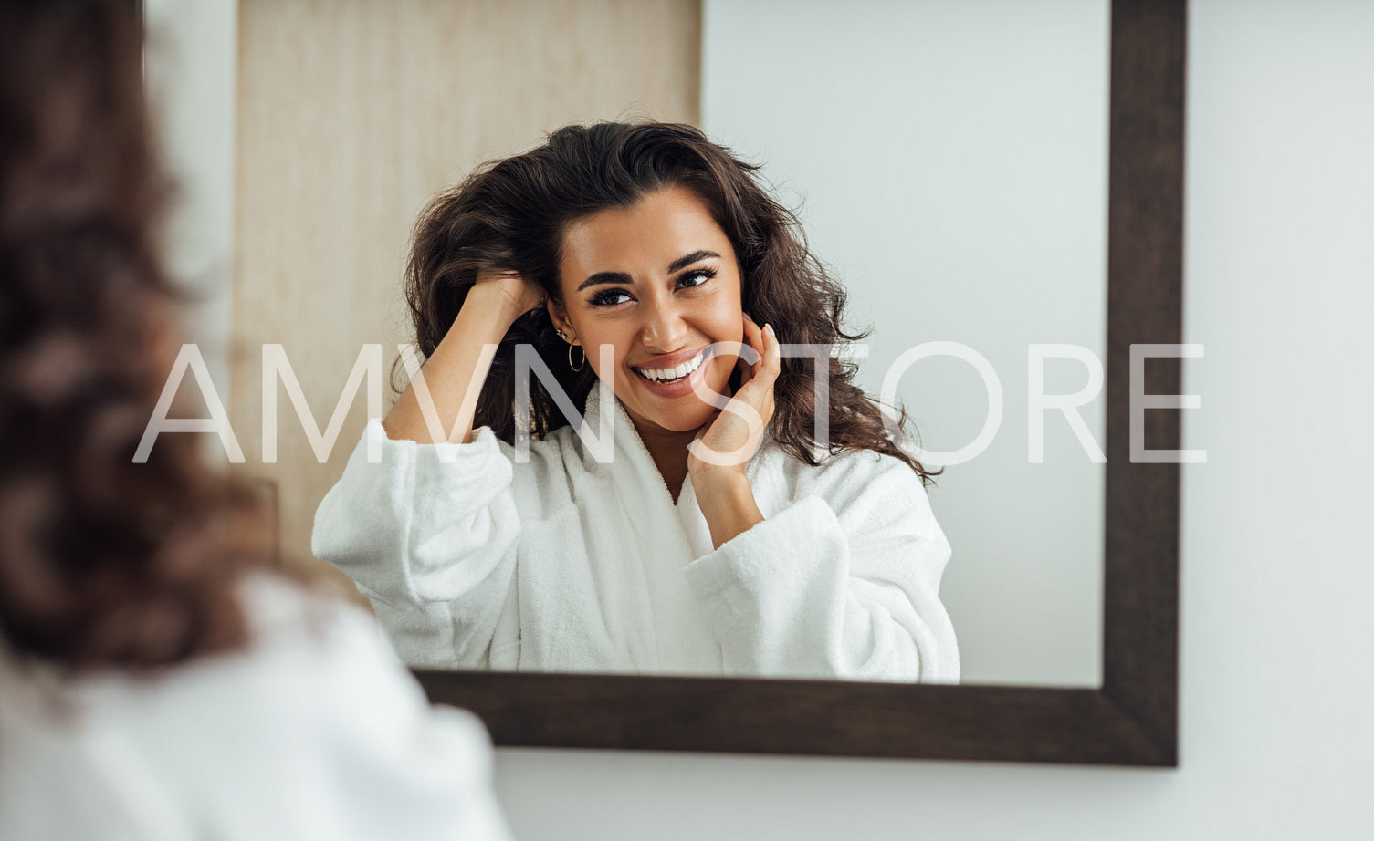 Beautiful middle east woman with long brown hair looking at a mirror in bathroom