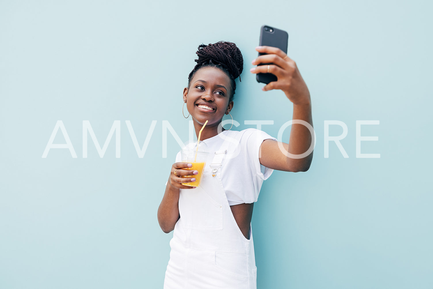 Happy woman in white casuals taking selfie holding orange juice