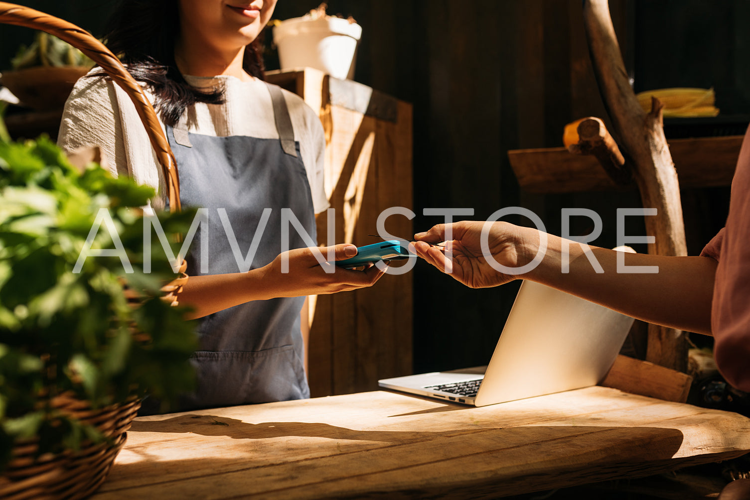 Vendor receiving payment from customer by card machine. Hands of unrecognizable women standing at a counter in an outdoor market and making a transaction.