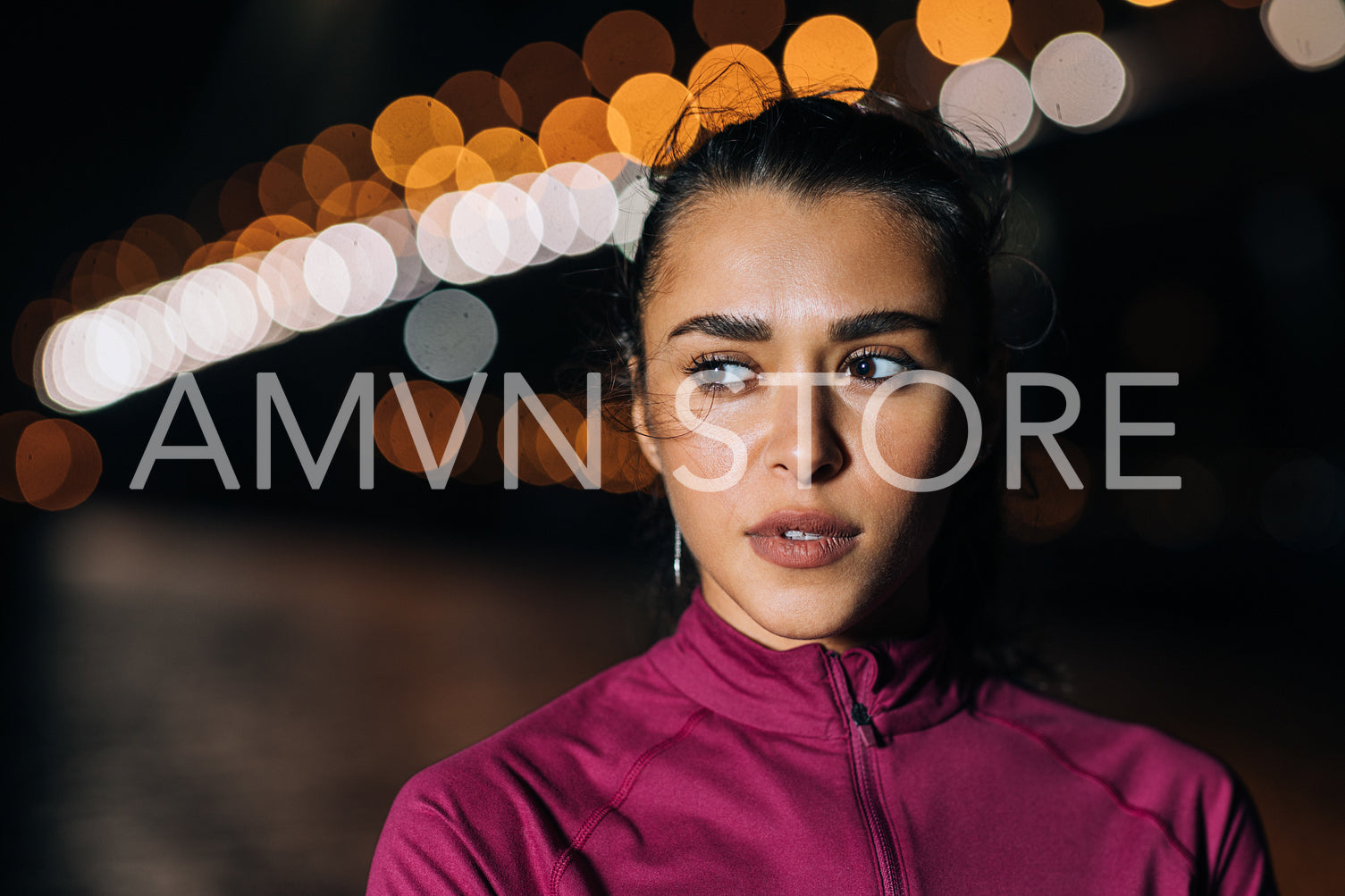 Portrait of a young sportswoman standing at night against city lights