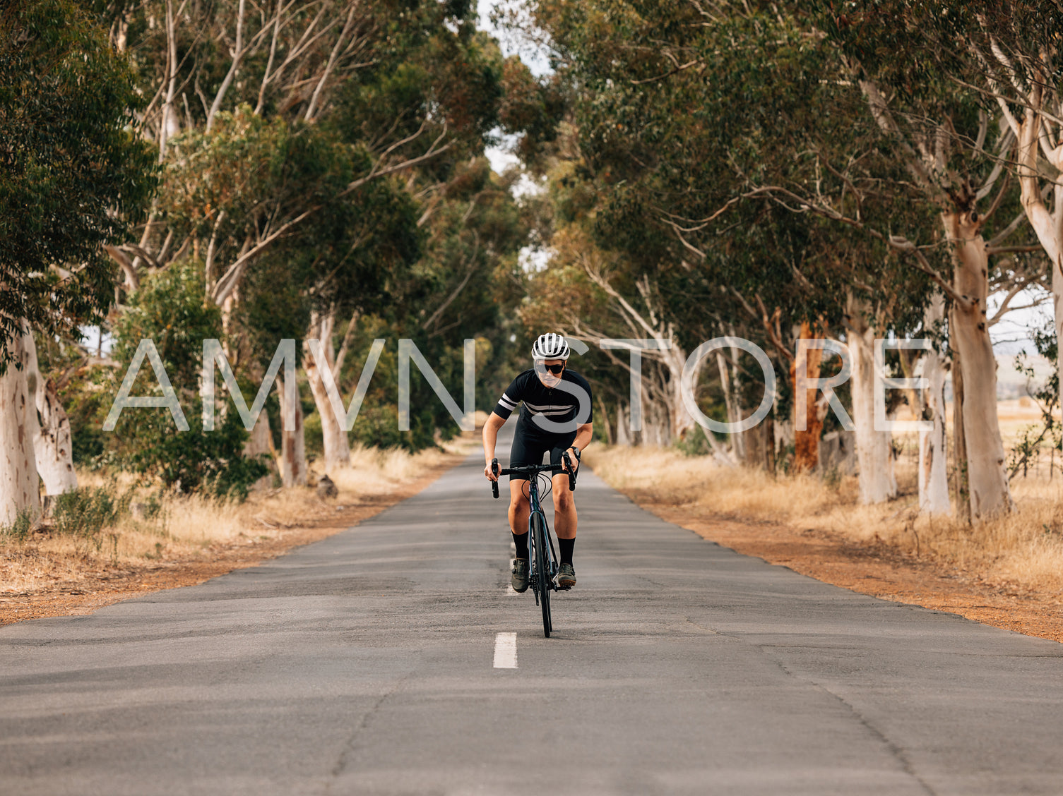 Professional female cyclist in sportswear riding bicycle on a centre of countryside road