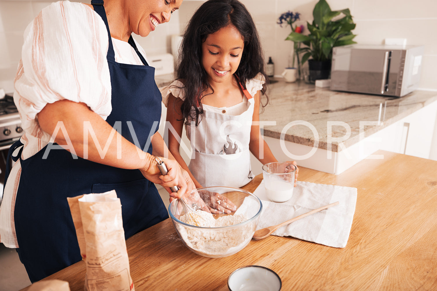 Mature woman showing her granddaughter how to mixing a dough