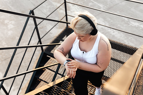 Hight angle view of a curvy woman stepping up on stairs checking pulse