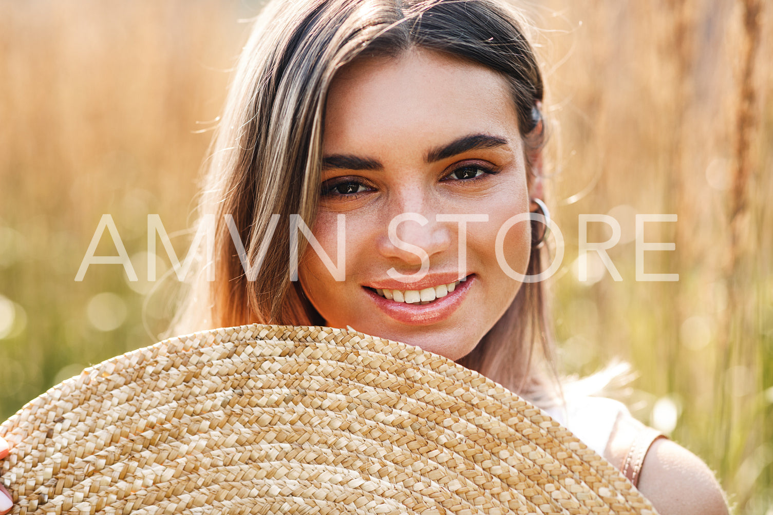 Close up portrait of a smiling woman holding a straw hat	