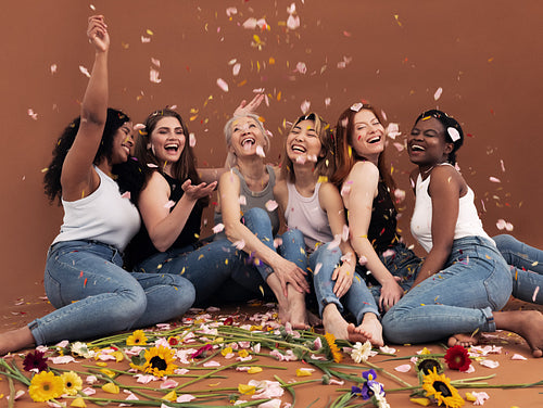 Multi ethnic group of happy women sitting under falling petals