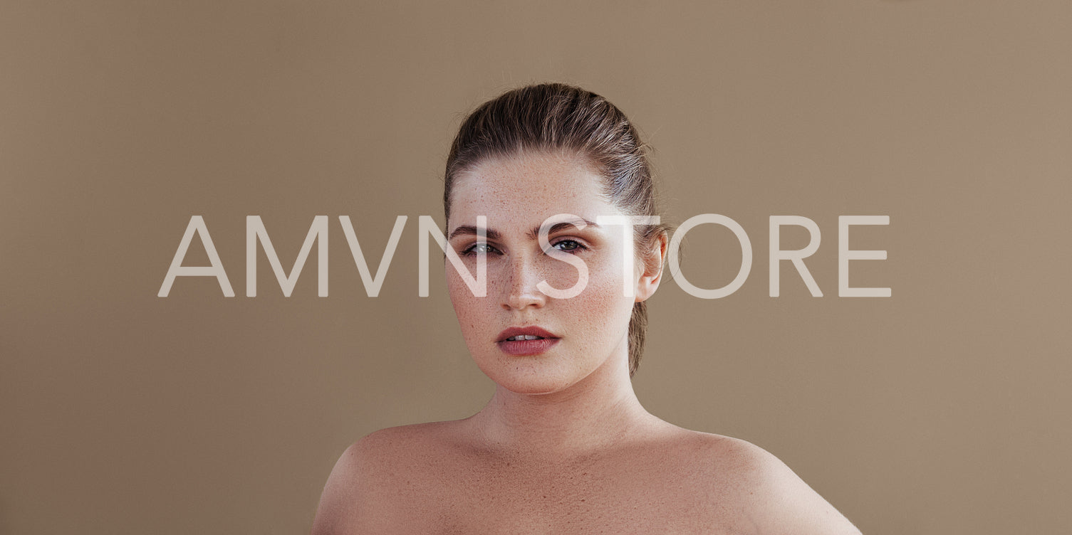 Portrait of a plus size woman posing over pastel backdrop. Young female with smooth skin looking at camera.