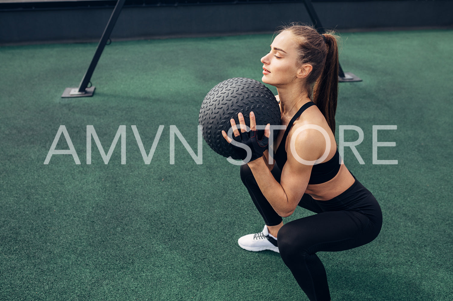 Side view of woman squatting with a medicine ball outdoors	
