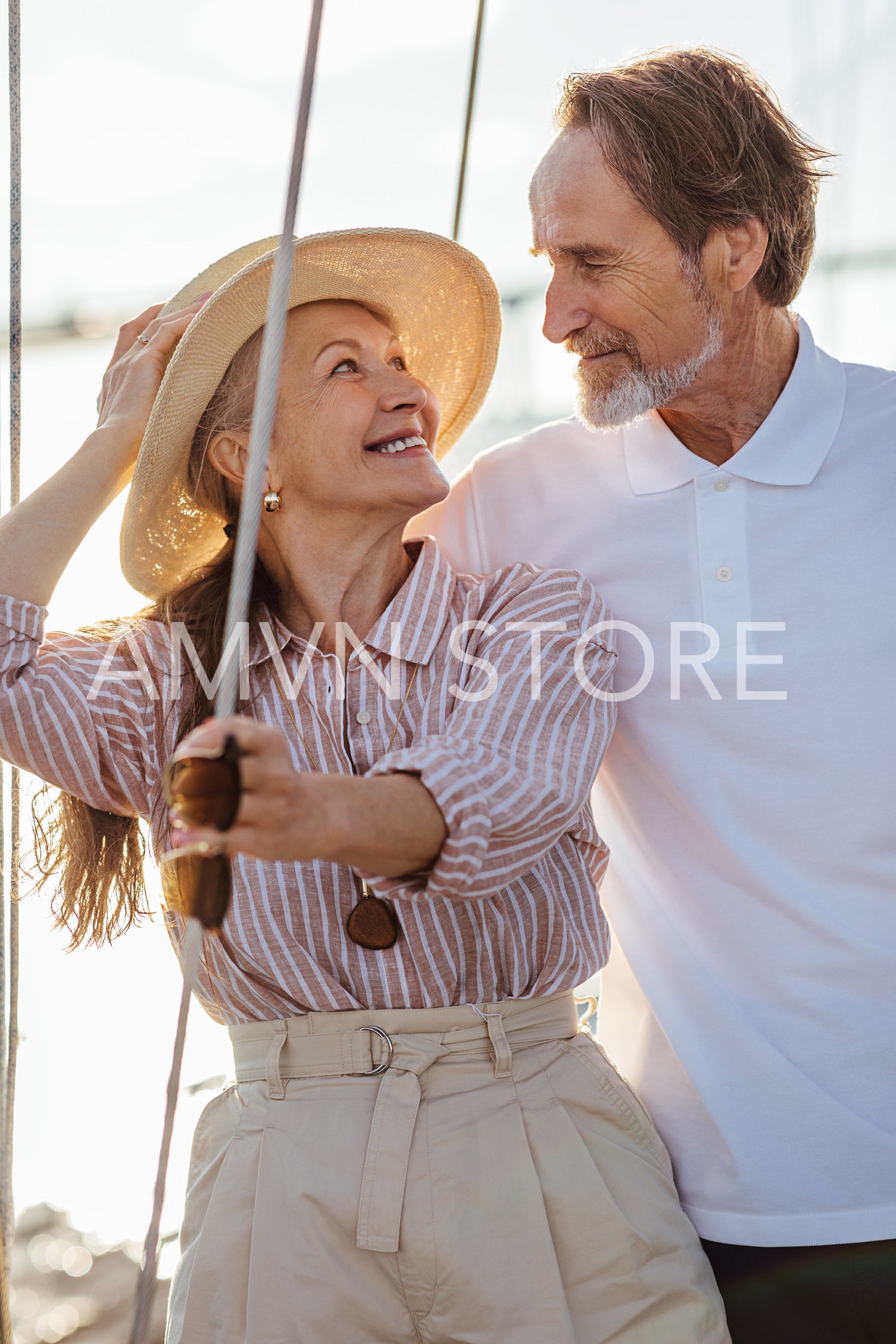 Romantic mature couple looking at each other while standing on a sailboat during sunny day	