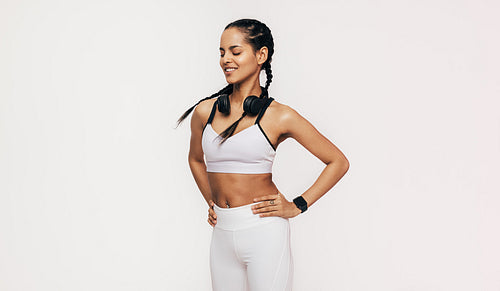 Smiling sportswoman with closed eyes standing in studio with hands on hips