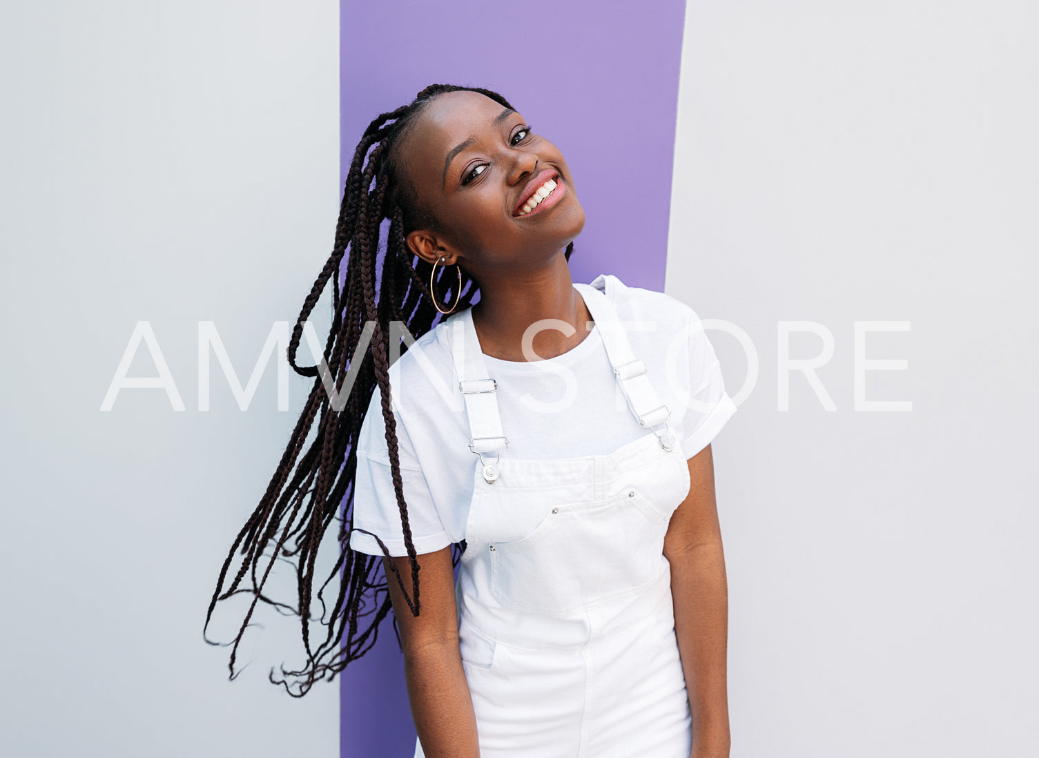 Young cheerful girl with braids in the white overall outdoors