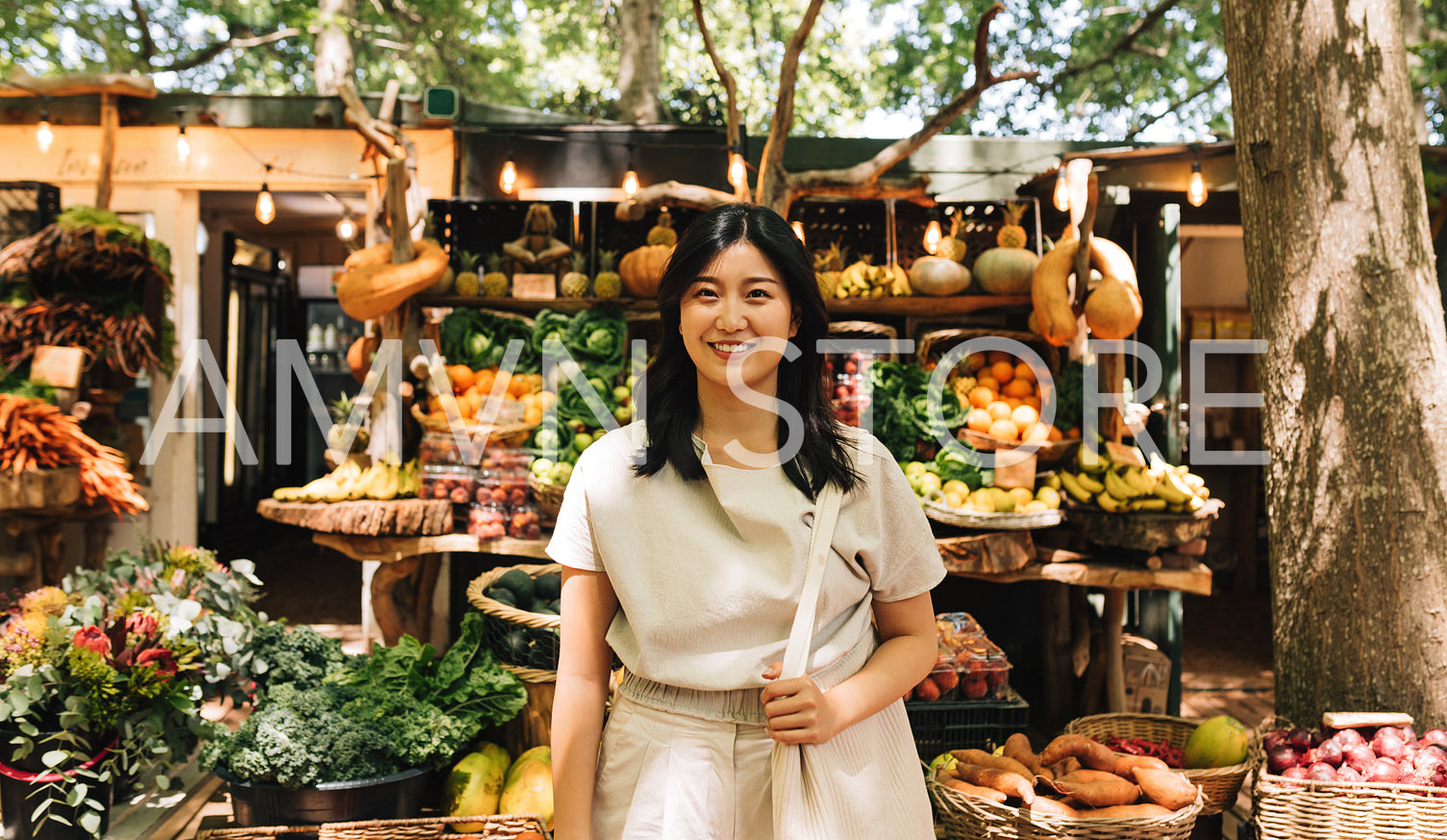 Portrait of a young Asian woman in casuals with a shopping bag on a farmers market