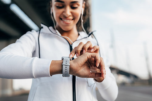 Close up of woman hand with a smartwatch. Smiling athlete checking results during fitness training.