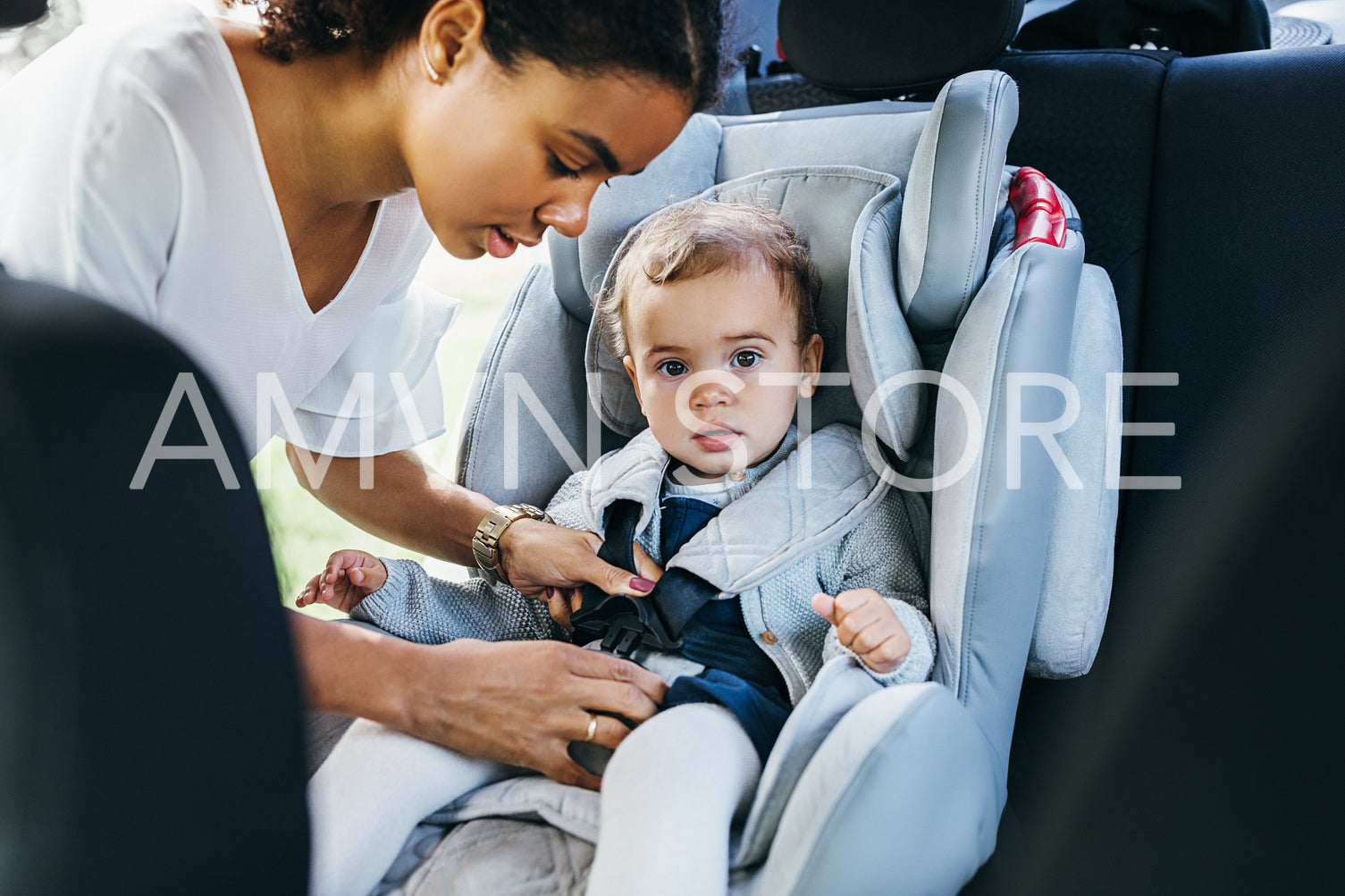 Cute little girl sitting on a baby seat in a car looking at the camera	