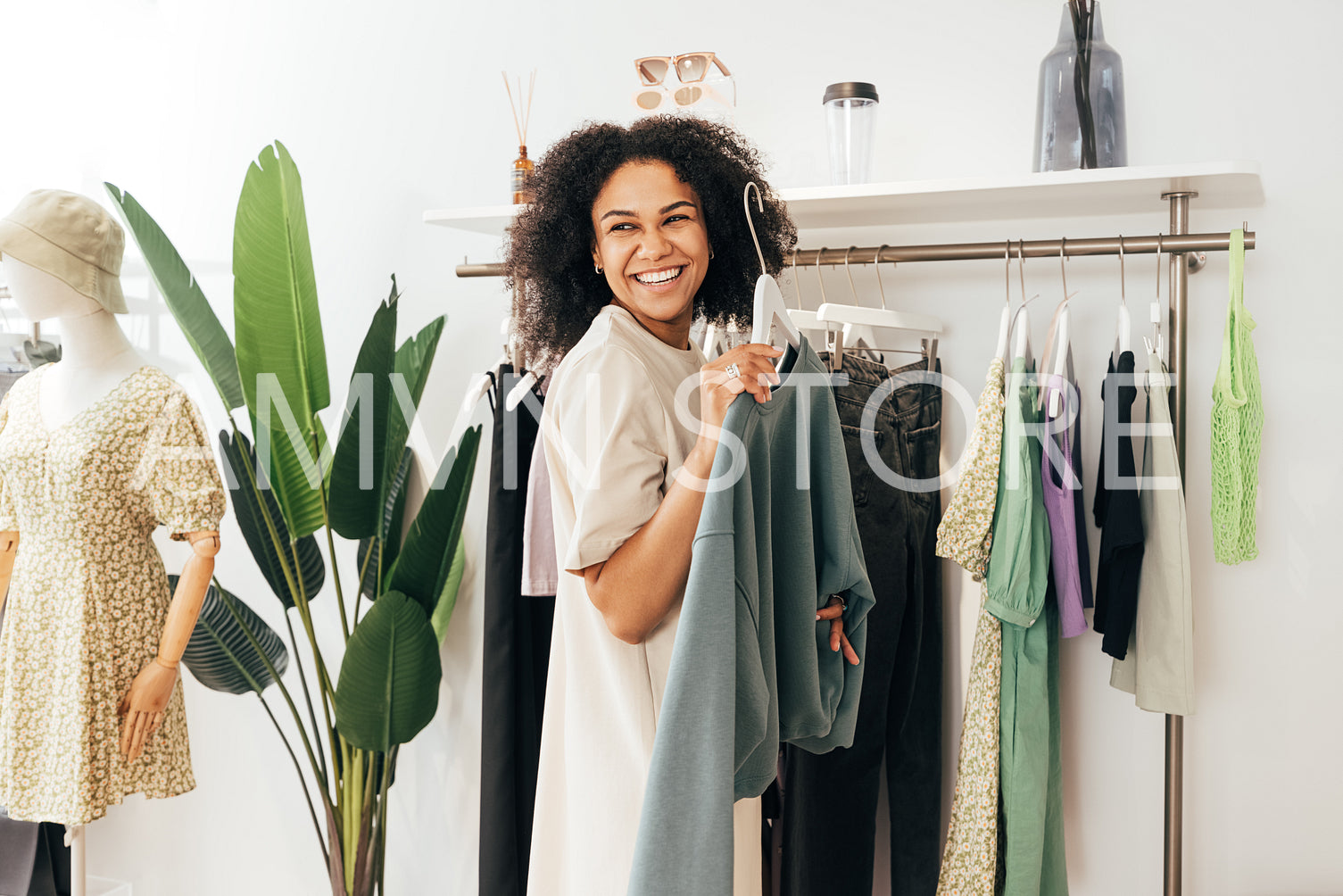 Laughing woman customer choosing sweatshirt in a small boutique