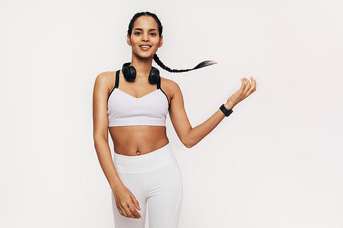 Smiling mixed race woman with braided hair wearing sports clothes posing over white background